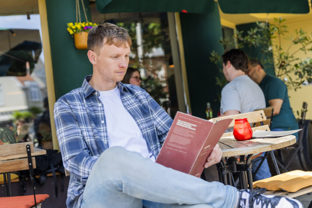 Man op terras kijkt naar menukaart