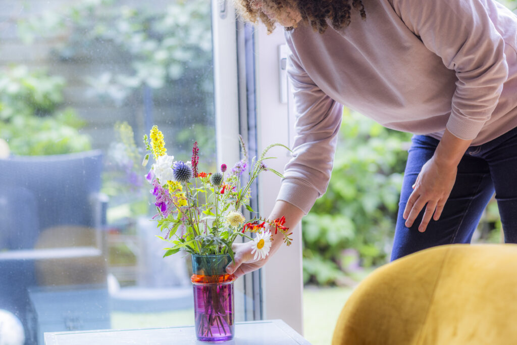 Vrouw zet vaas met bloemen neer